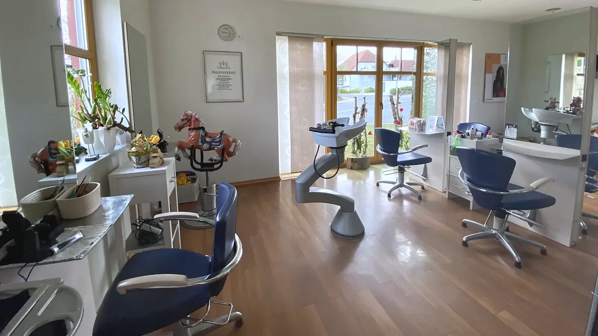 Salon mit blauen Frisierstühlen, Spiegeln und Holzfußboden