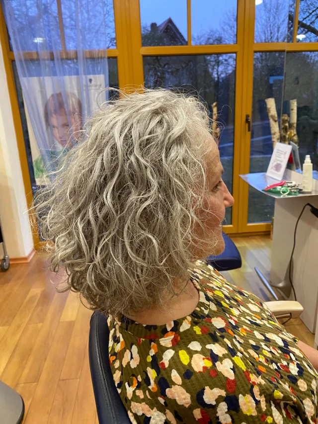 Graublonde Wellen und Locken von hinten im Salon